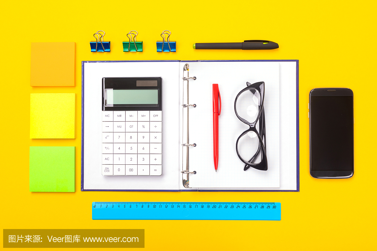 俯视图的工作空间桌子与手机,笔记本和钢笔孤立在黄色的背景